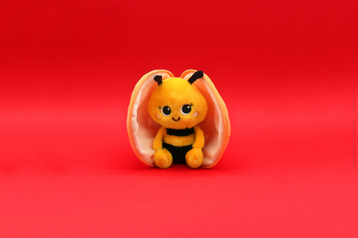 Small plush bee toy inside an orange tangerine-style pouch.