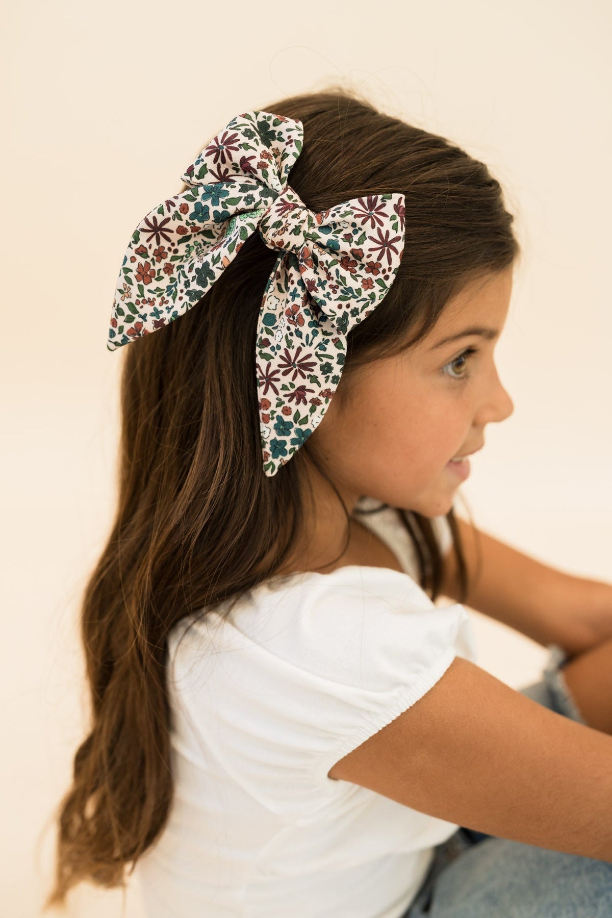 Floral hair bow with multicolor print tied on long brown hair