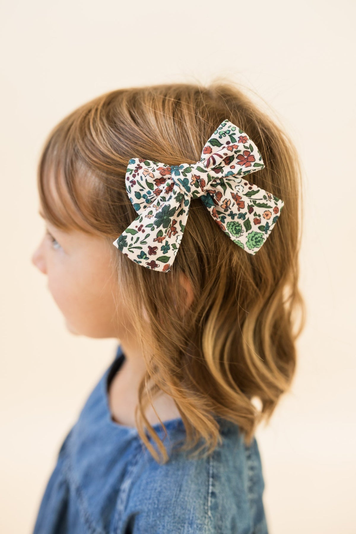 Petite hair bow on blonde hair; cream floral print with leafy accents