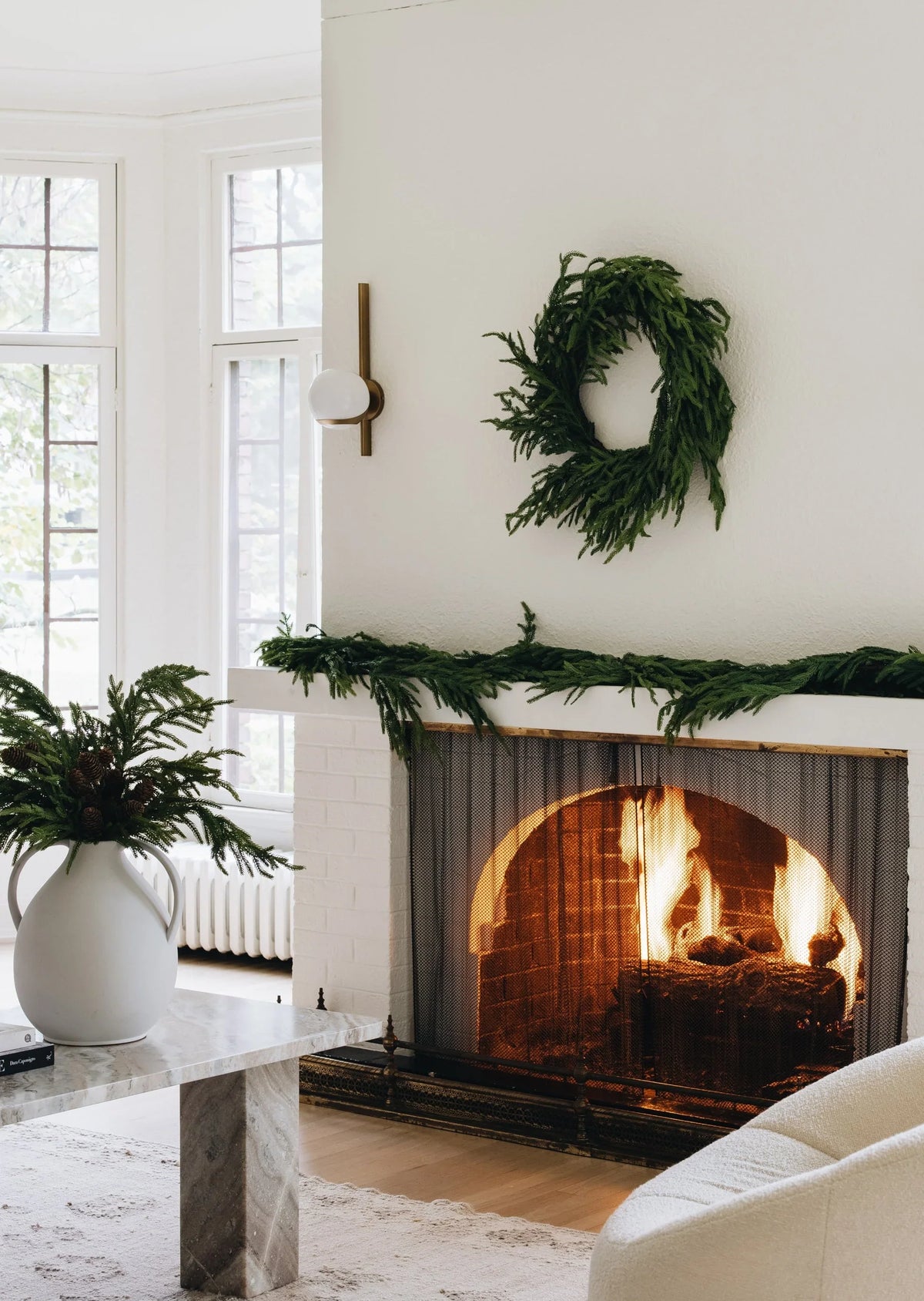 Green faux pine Christmas wreath above a fireplace mantel.