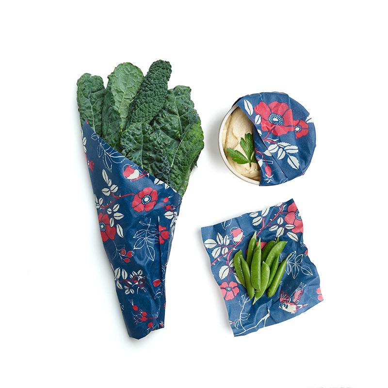 Reusable floral food wraps in navy with red flowers and green leaf faces, folded