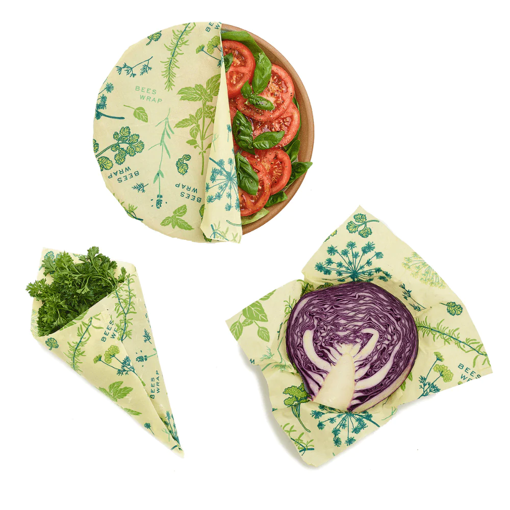 Bee’s Wrap wax food wraps with green botanical print holding sliced tomatoes and cabbage