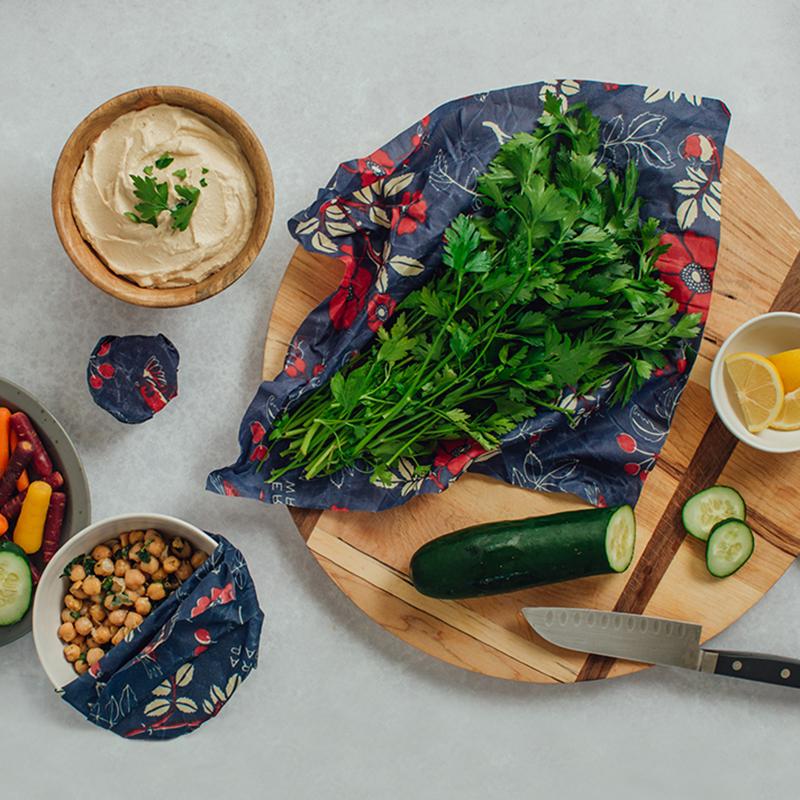 Bee’s Wrap wax food wraps with navy botanical print and herbs on wooden board