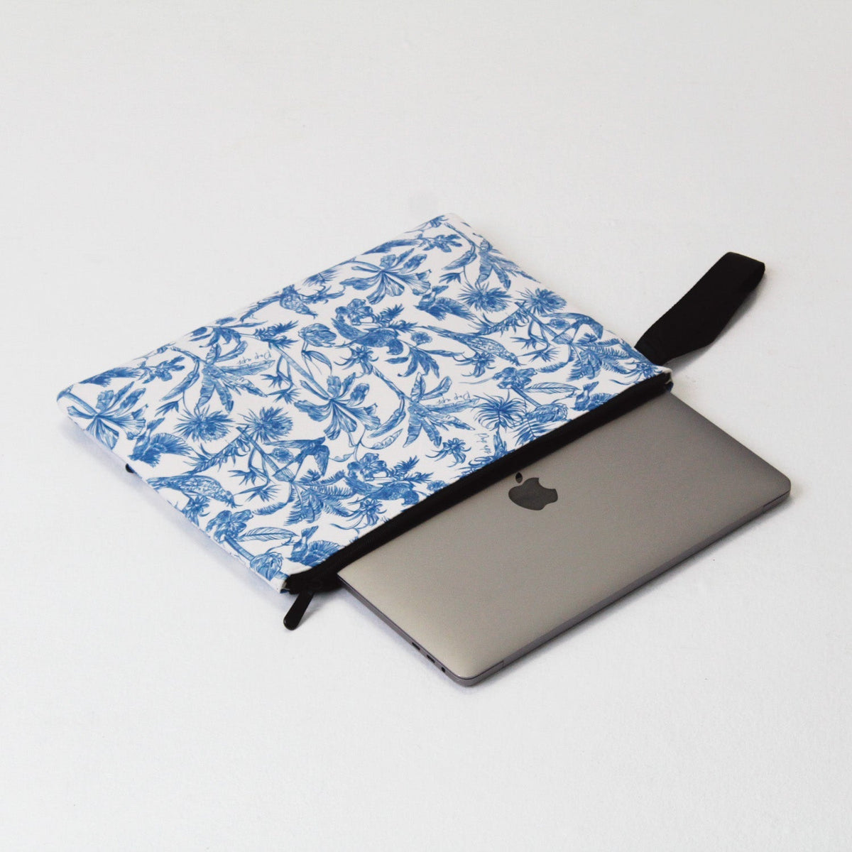 Blue and white toile laptop sleeve with black strap, holding a laptop