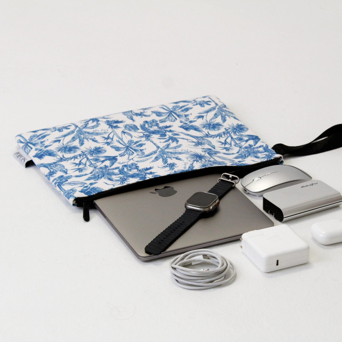 Blue and white toile laptop sleeve with zipper, holding laptop and accessories