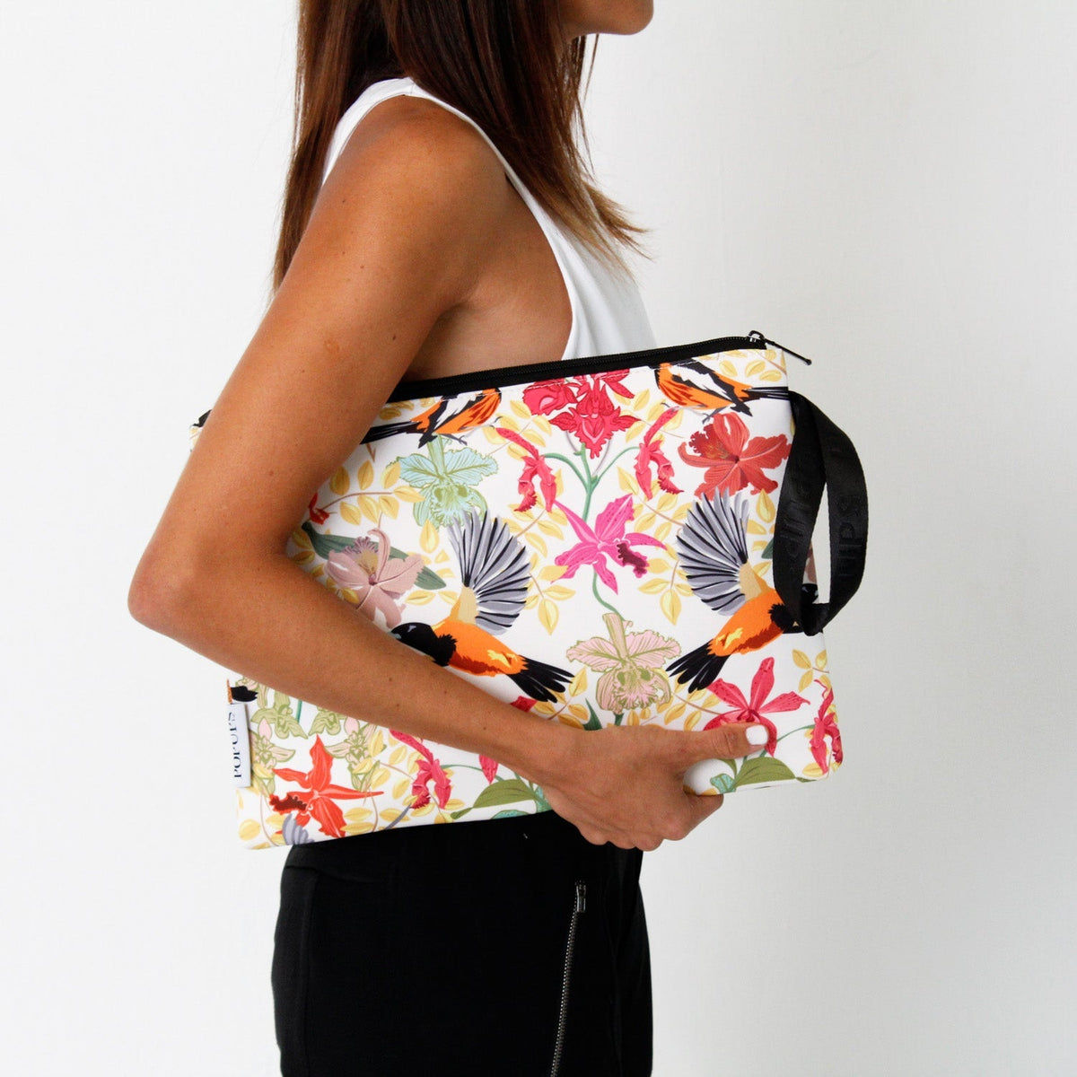 Tropical print laptop sleeve with black handle and zipper, held by the strap