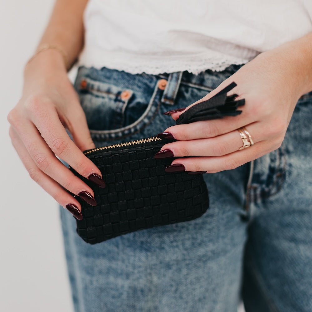 Black textured card wallet with gold zipper and tassel.