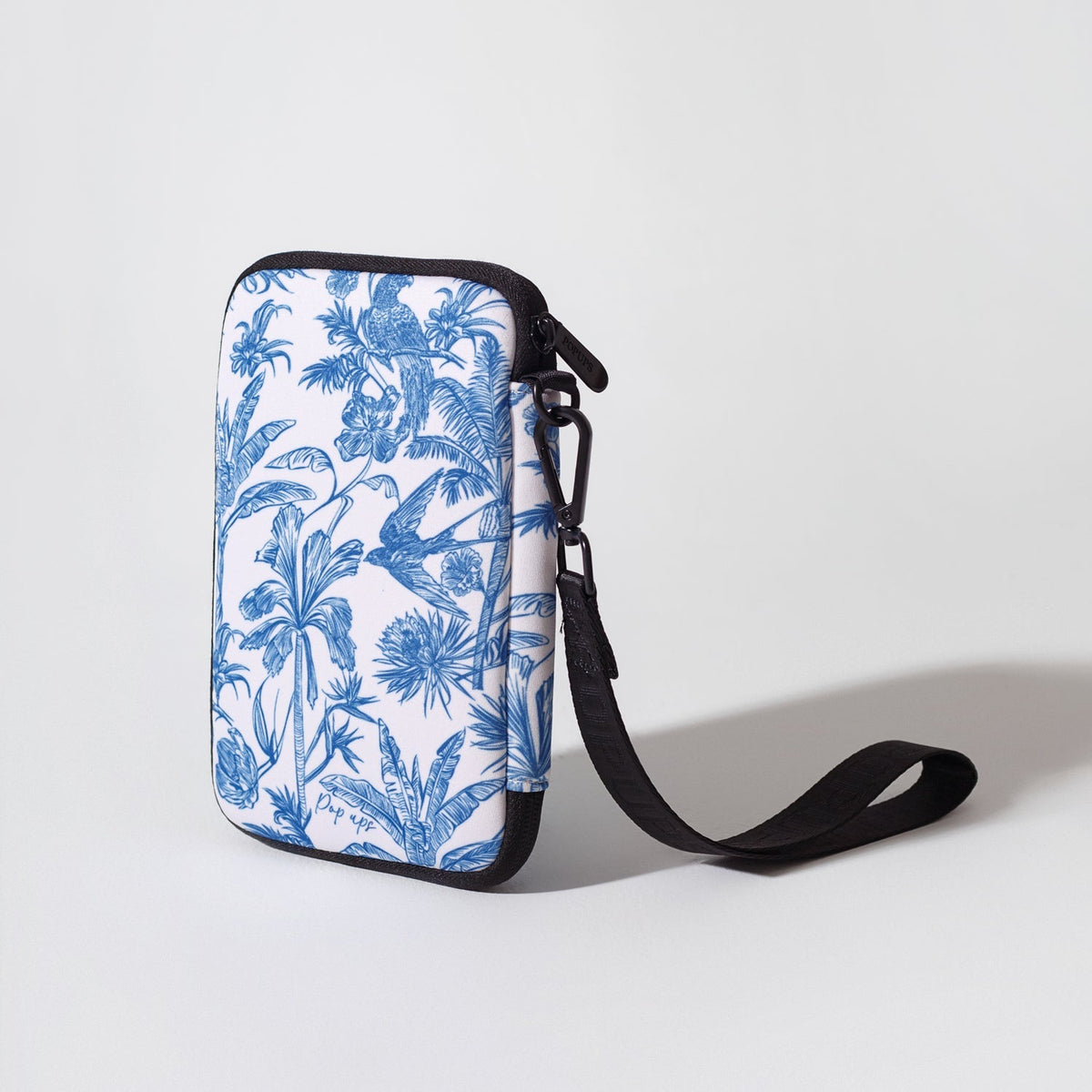 Blue tropical print passport wallet with black zipper and crossbody strap