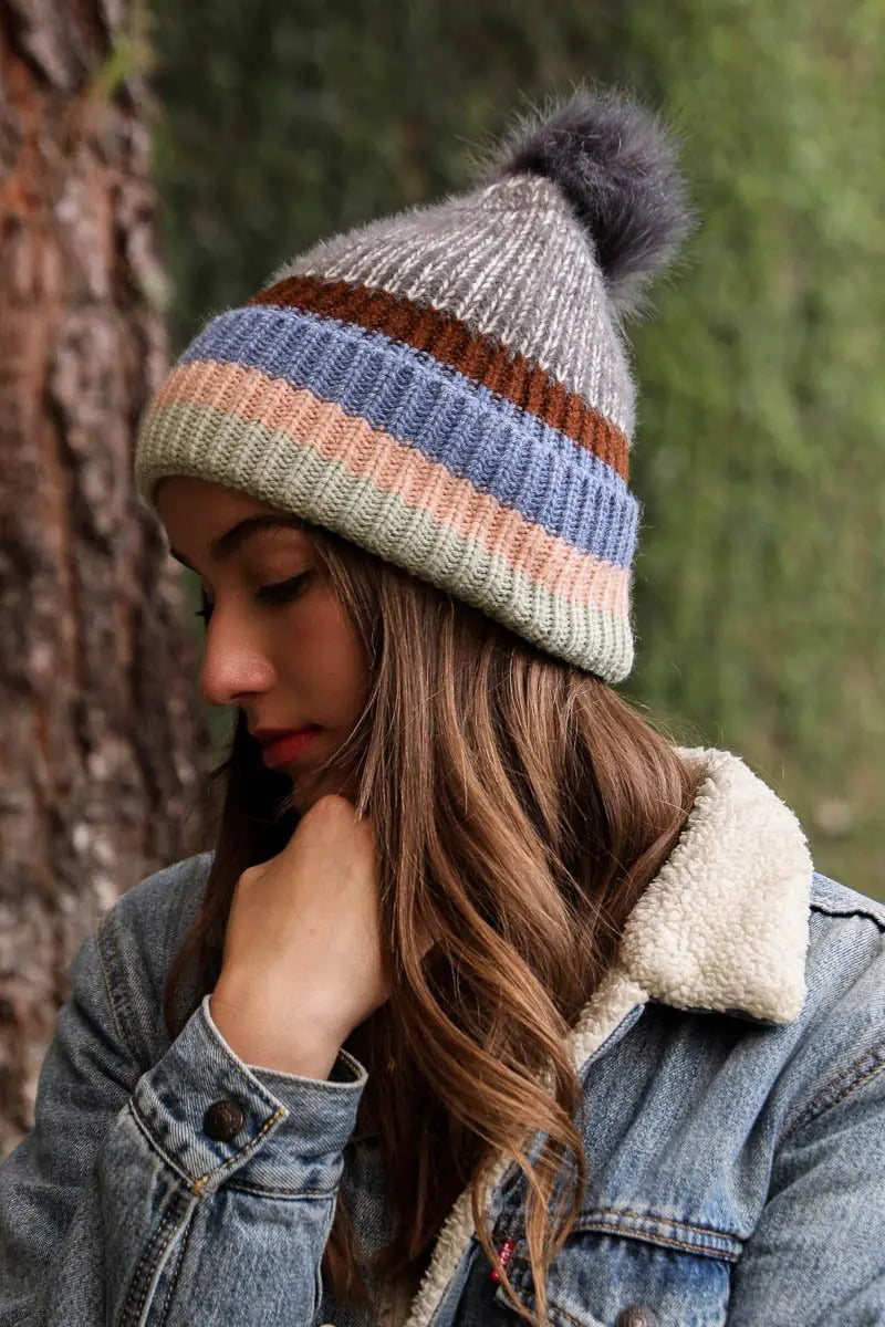Pastel striped knit beanie with pom-pom; gray knit with rust and blue stripes