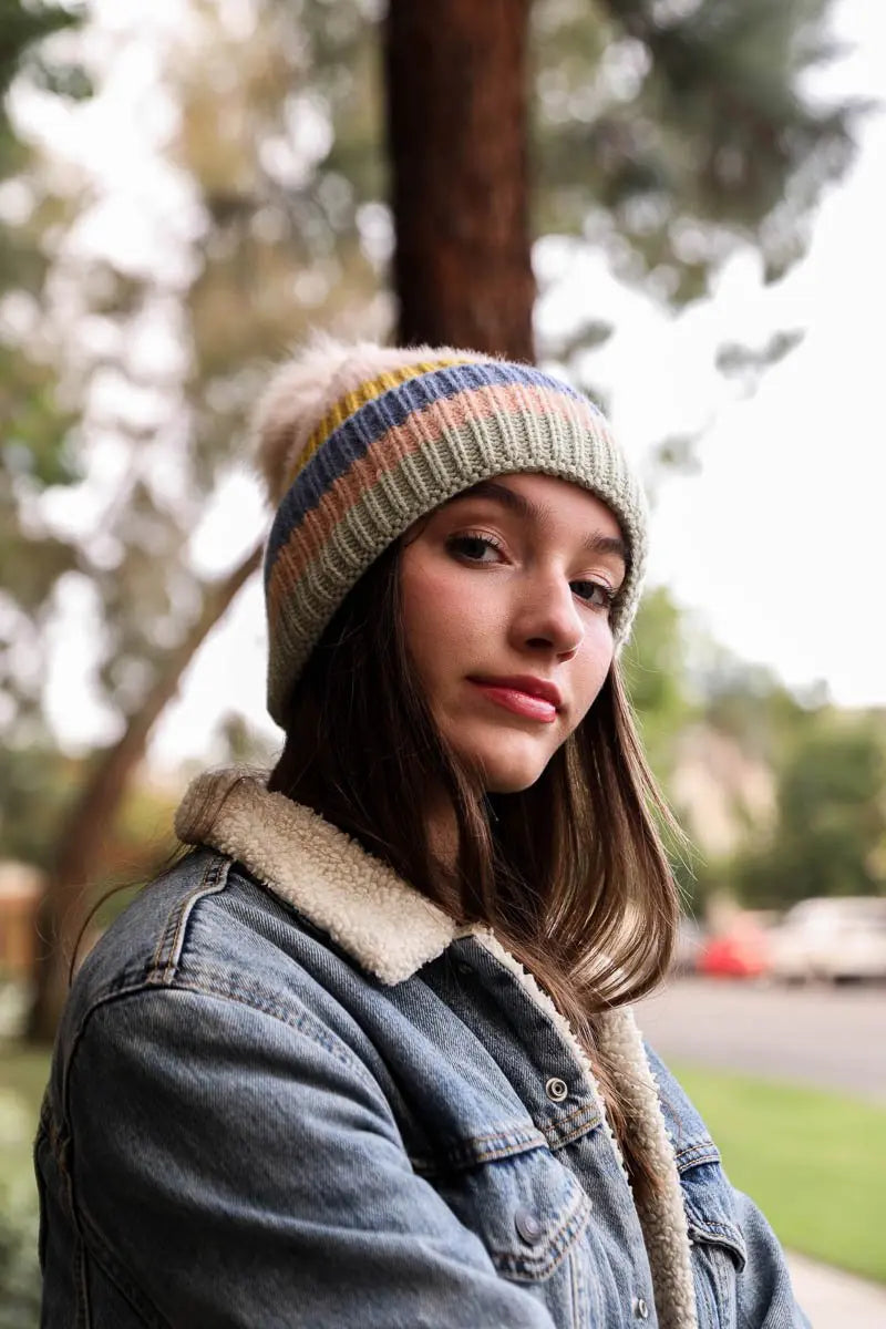 Pastel striped knit beanie with pom-pom; gray knit with blue and pink stripes