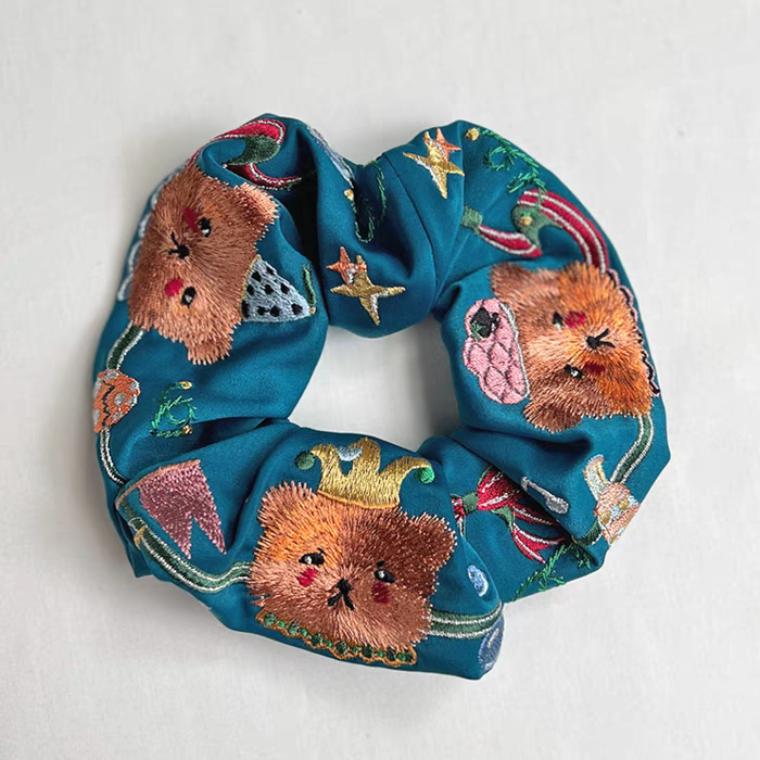 Teal blue scrunchie with embroidered circus bear faces and star motifs