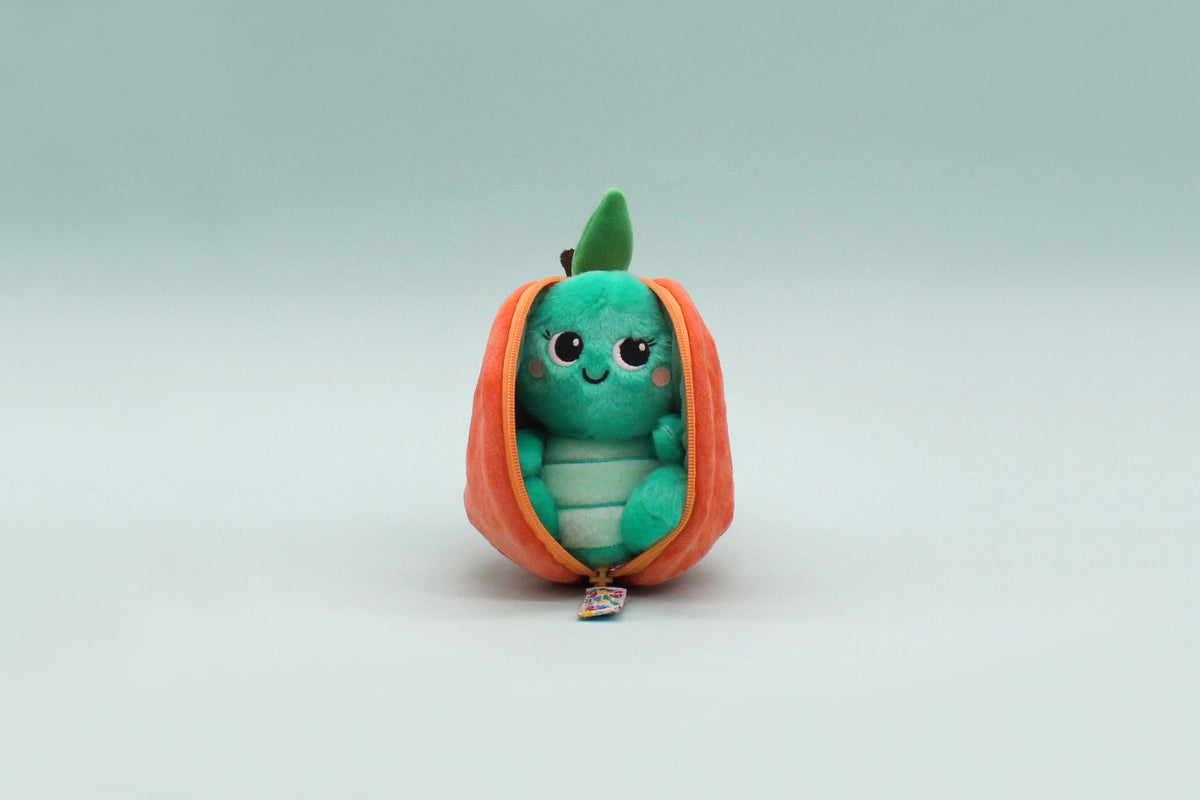 Small green plush turtle inside peach orange flip-top pouch