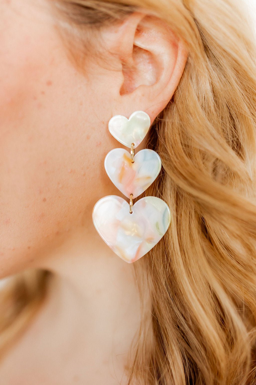 Pastel layered heart drop earrings on gold hooks, shown from the side