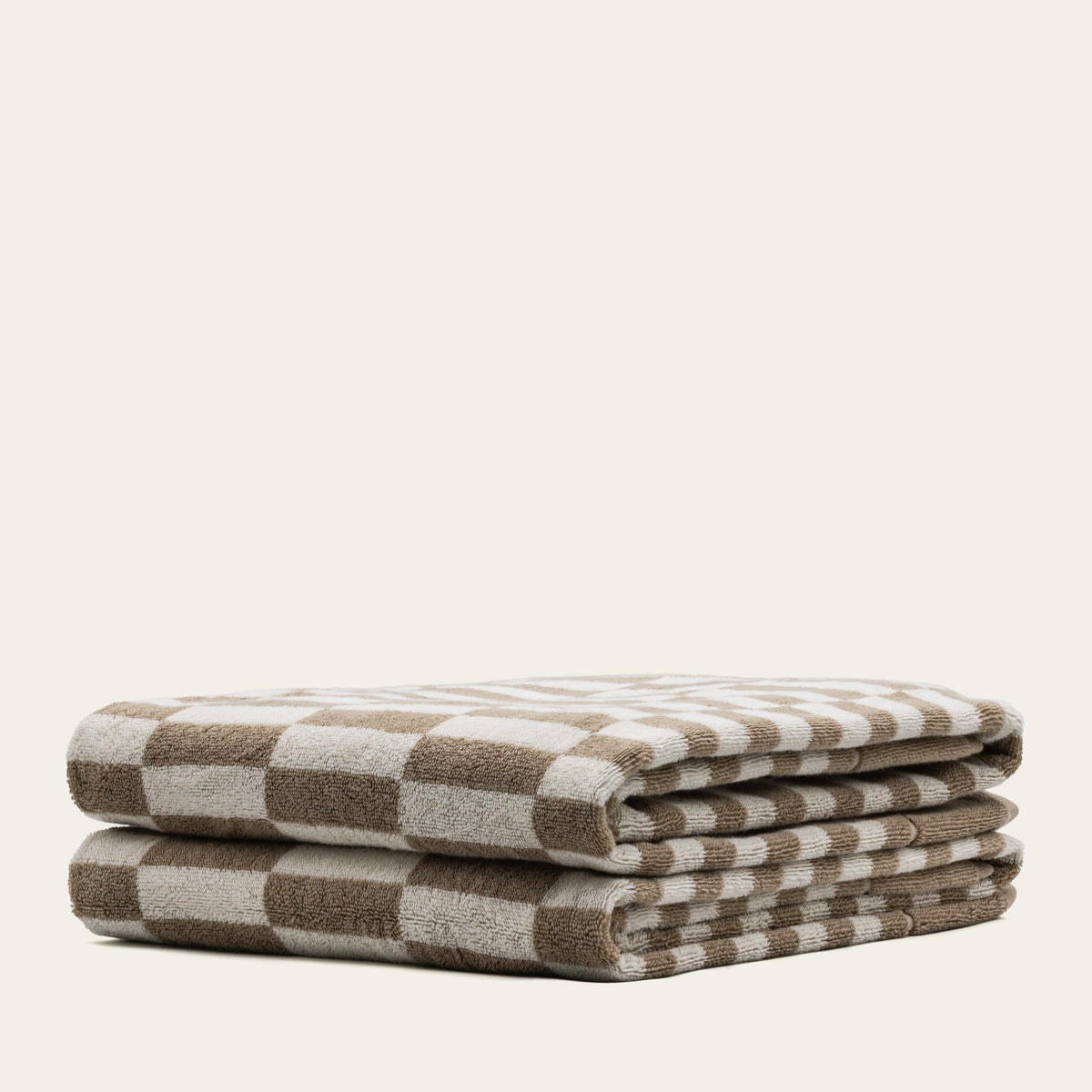 Single folded cotton towel with tan and ecru striped pattern, neat stack