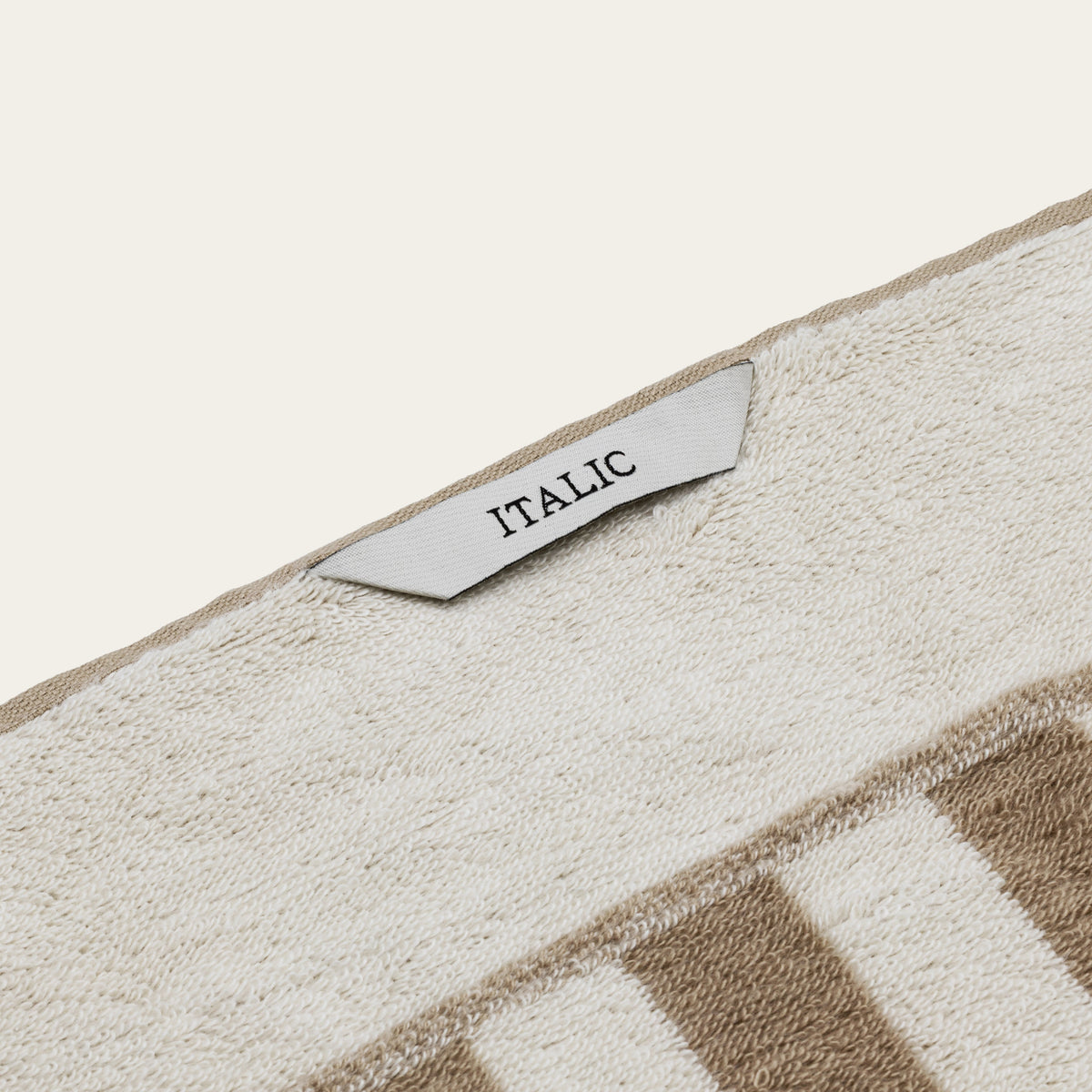 Close-up of soft cotton towel with stitched label on tan-and-ecru texture