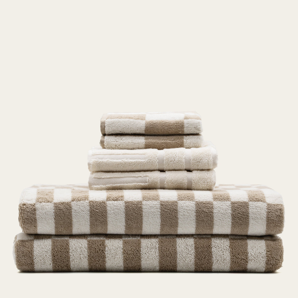Stack of cotton towels with alternating tan and ecru stripes and check design