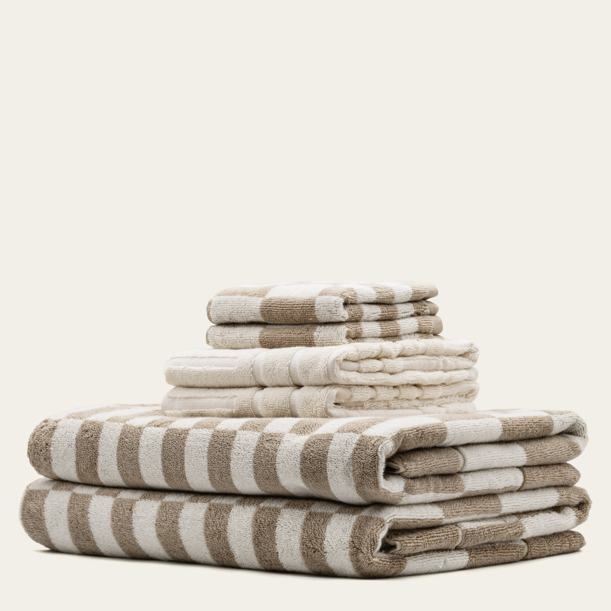 Folded cotton towel set with tan-and-ecru stripes and stacked layers