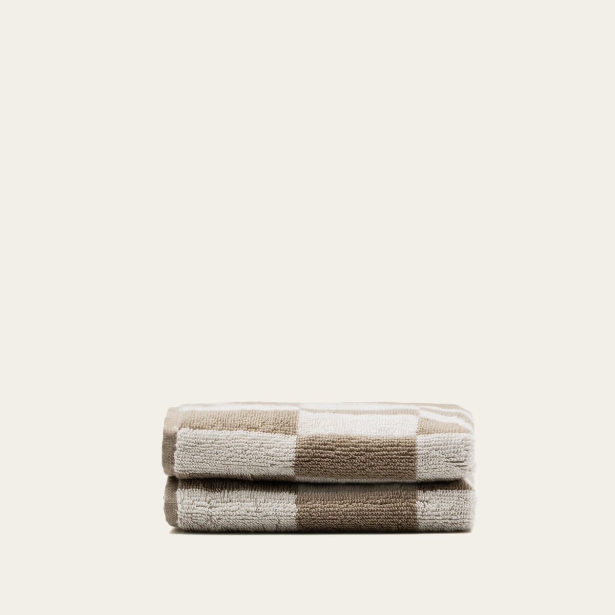 Tan and ecru checkered cotton towels, folded into a compact stack