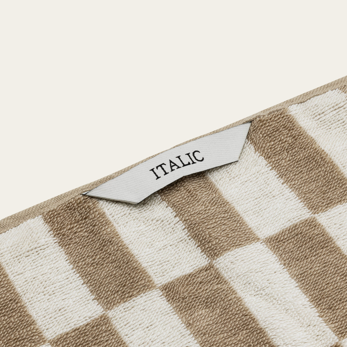 Tan-and-ecru checkered towel with woven border and brand tag