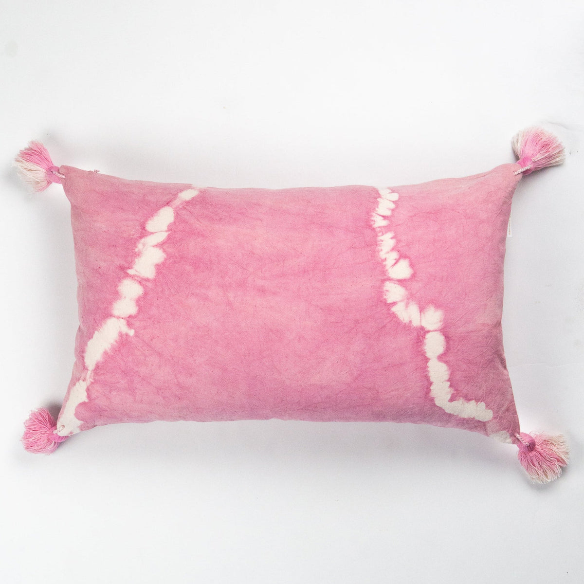 Pink shibori tie-dye lumbar pillow with white drip pattern and tassel fringe corners.