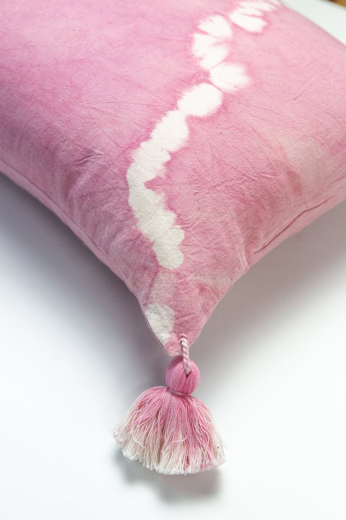 Pink shibori pillow corner with white swirl band and small round tassel trim.