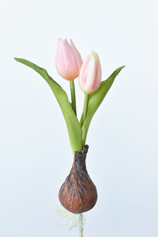 Three soft pink tulips with green stems from a faux bulb on a pick