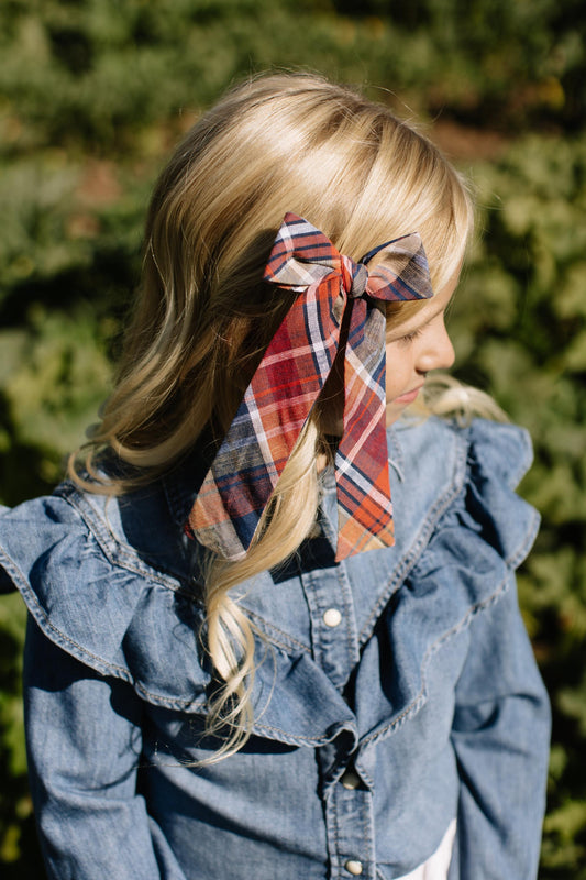 Plaid lady hair bow tied at the side of blonde hair with long ribbon ends