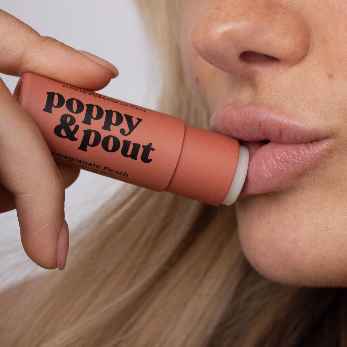 Pomegranate peach lip balm being applied in close-up on lips