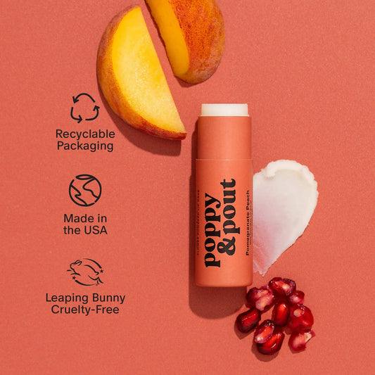 Pomegranate peach lip balm stick with exposed balm and sliced fruit