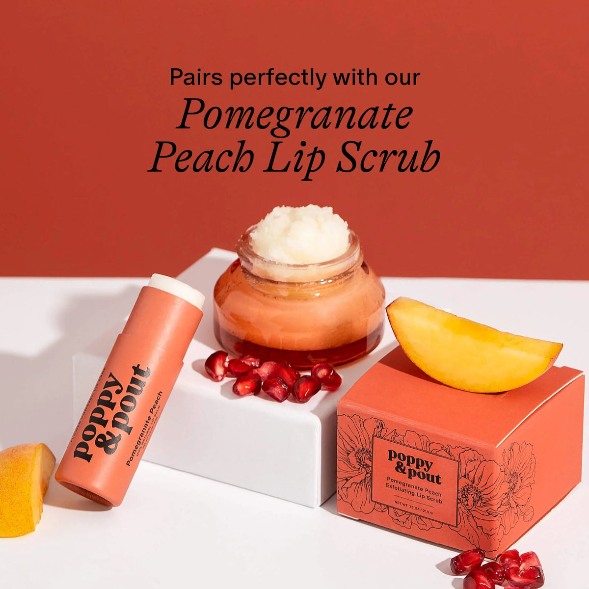 Pomegranate peach lip balm tube beside gift box and fruit accents