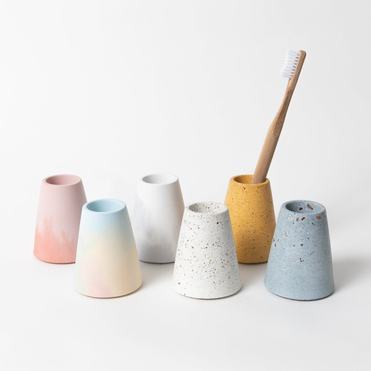 Pastel ceramic toothbrush holder set with four cups and upright toothbrushes