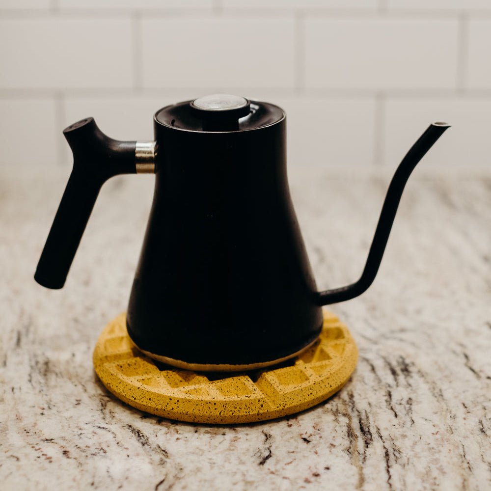 Black gooseneck coffee pot on marigold terrazzo waffle trivet with diamond pattern
