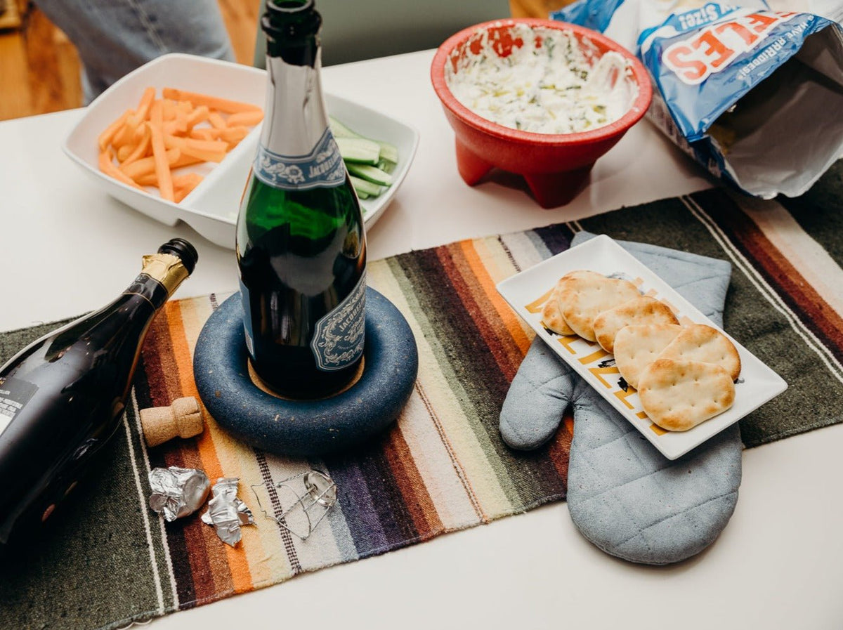 Quilted light blue oven mitt trivet placed on a table near food and drinks