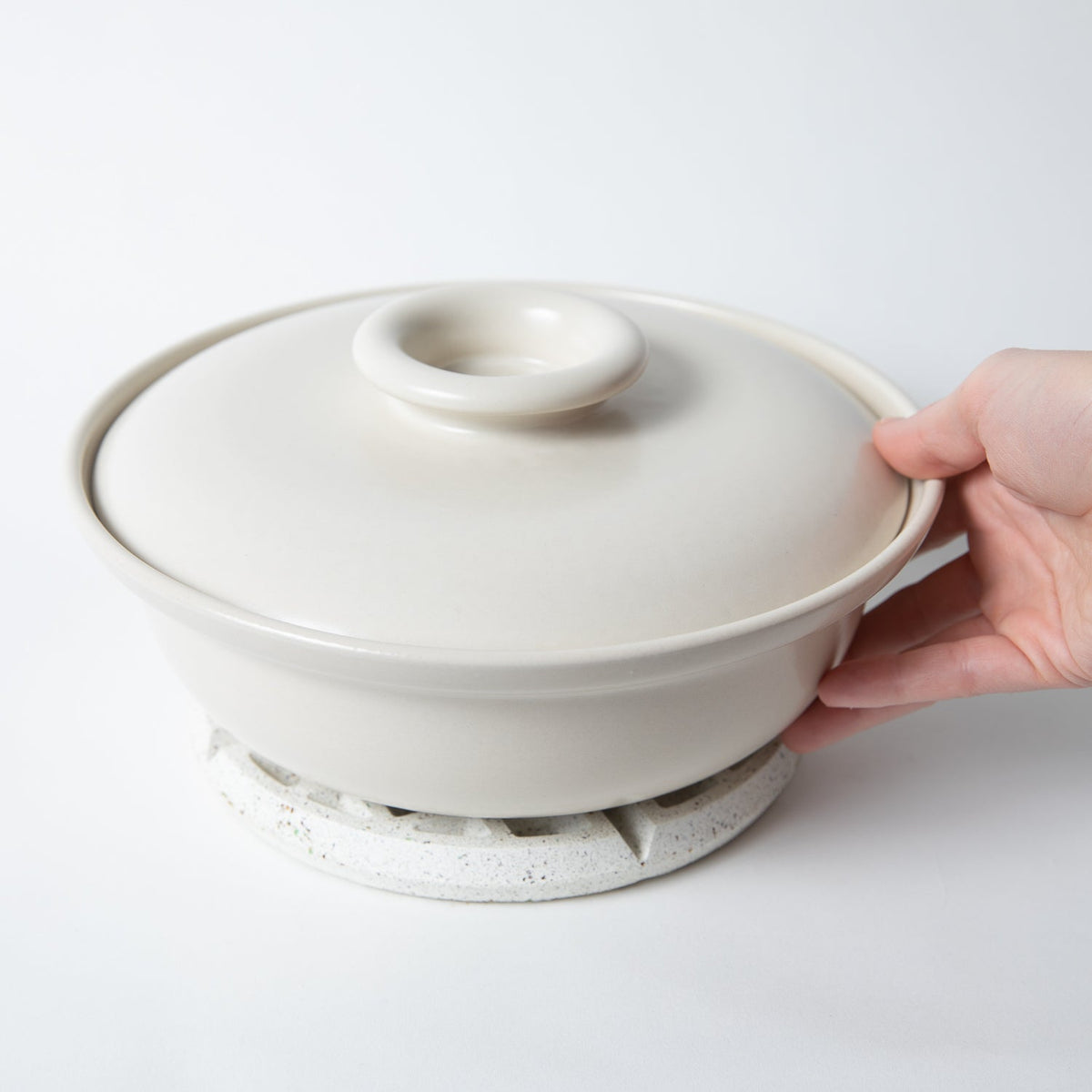 White terrazzo trivet under a white pot lid