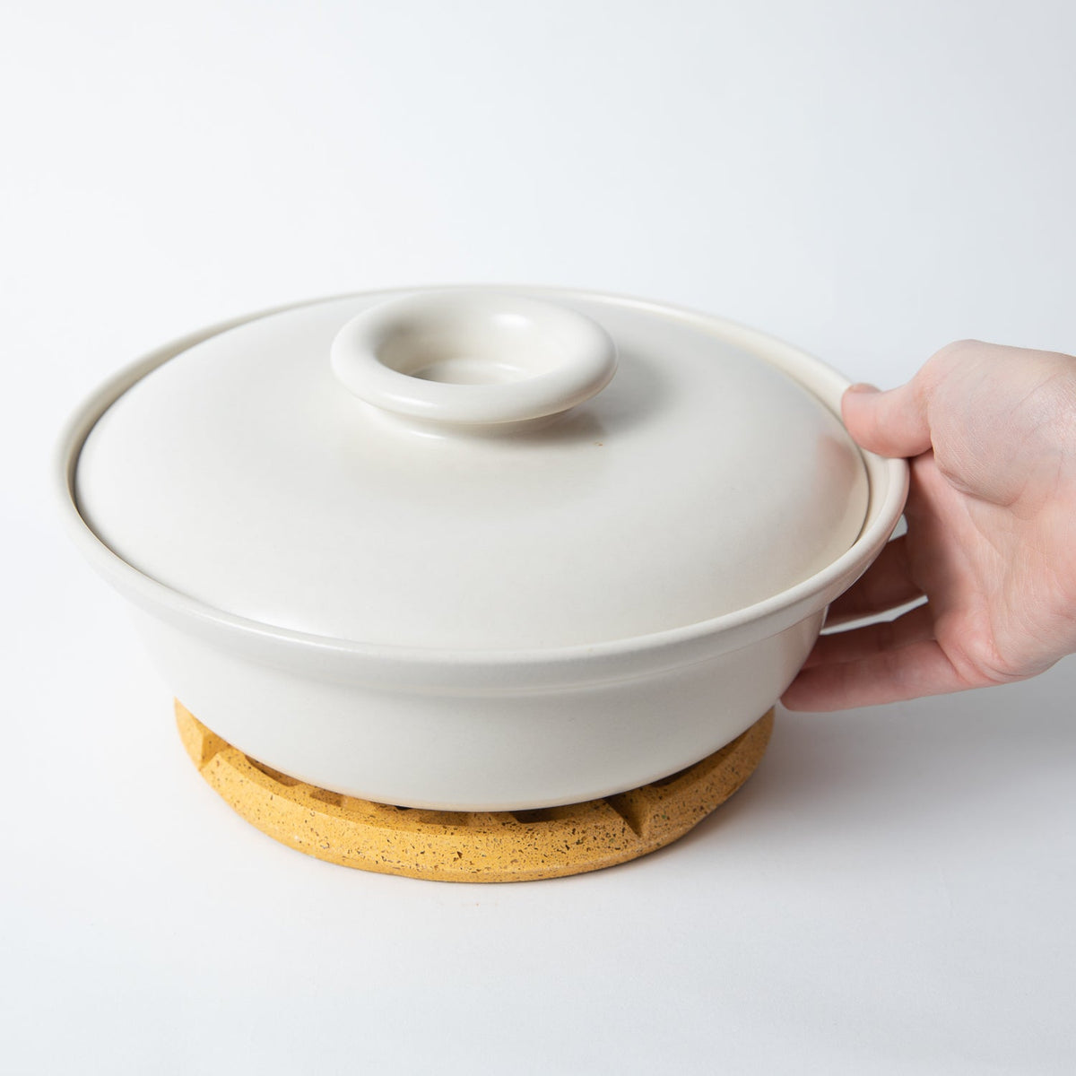 Marigold terrazzo waffle trivet supporting a white pot lid