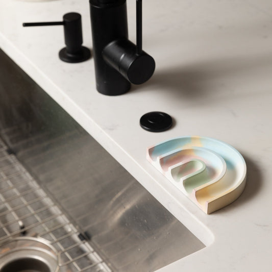 Multi-color sponge rest with open slot, placed on a countertop edge