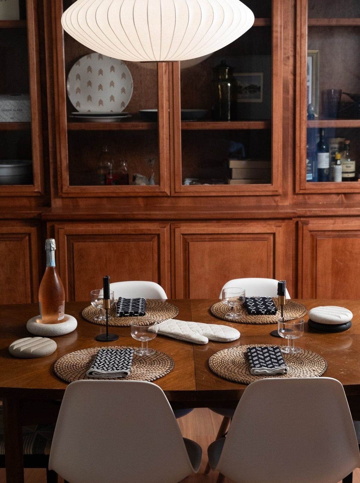 White quilted oven mitt on a wooden table among other kitchen trivets.