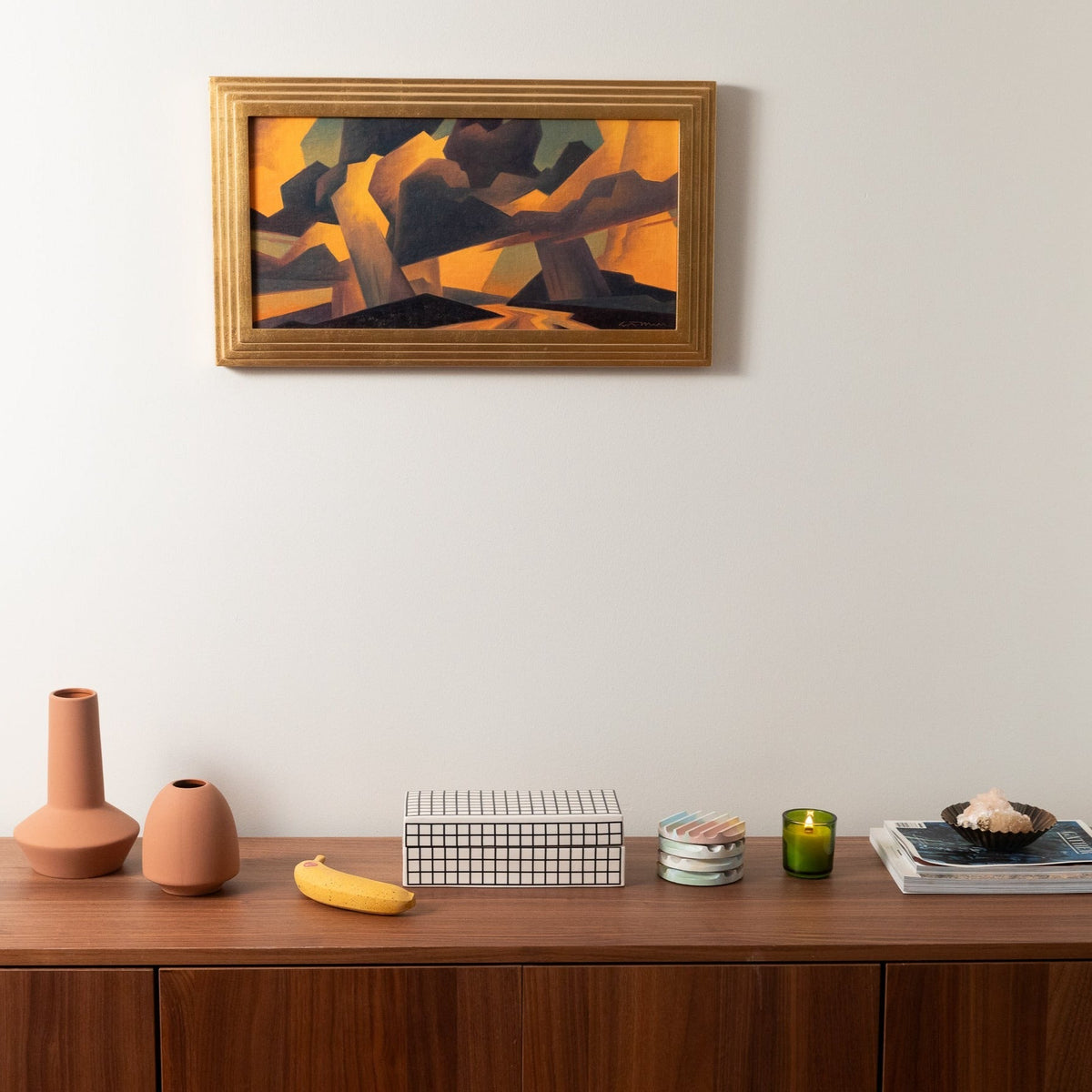 Concrete banana sculpture on wooden surface, small yellow banana figure with red emblem.