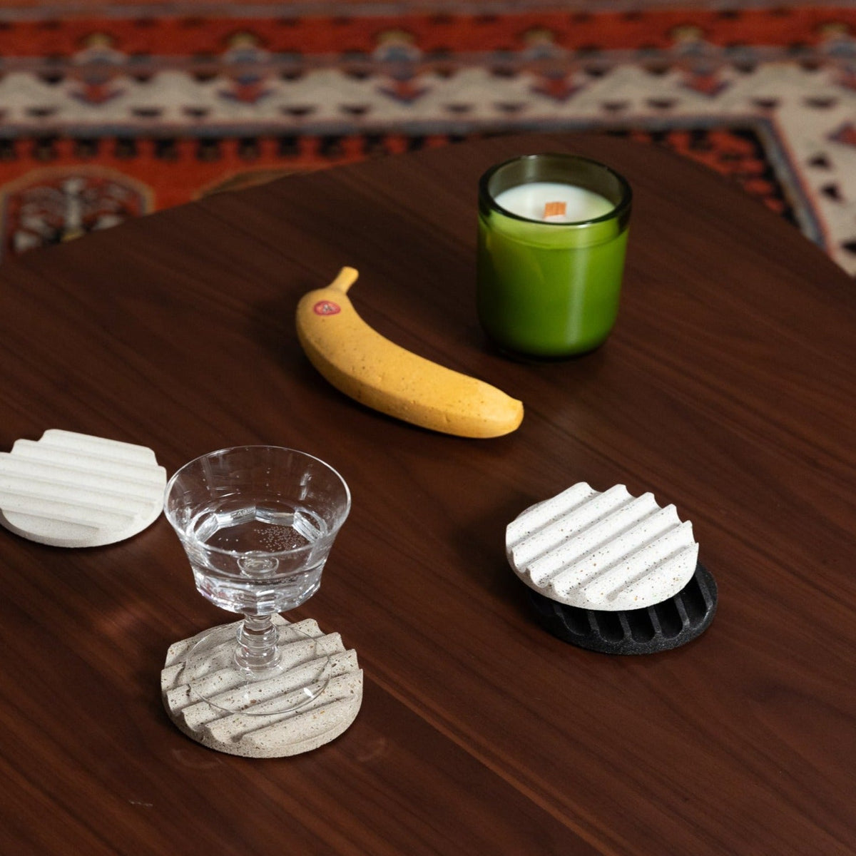 Concrete banana sculpture with small red emblem on yellow speckled surface, on table.