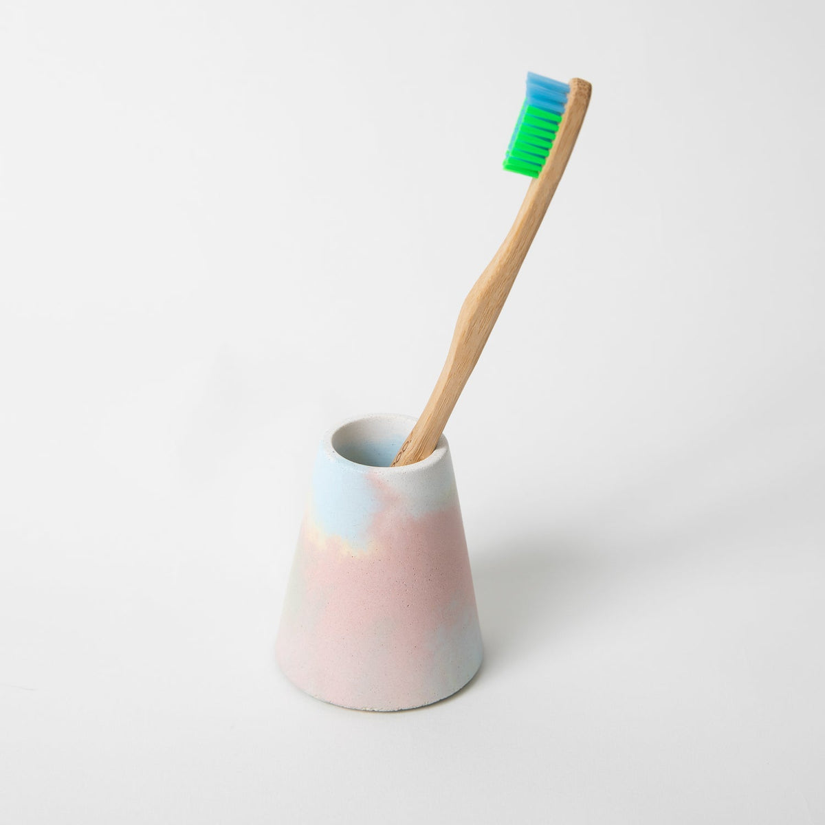 Jawbreaker toothbrush holder in pastel pink ceramic cup with upright green toothbrush