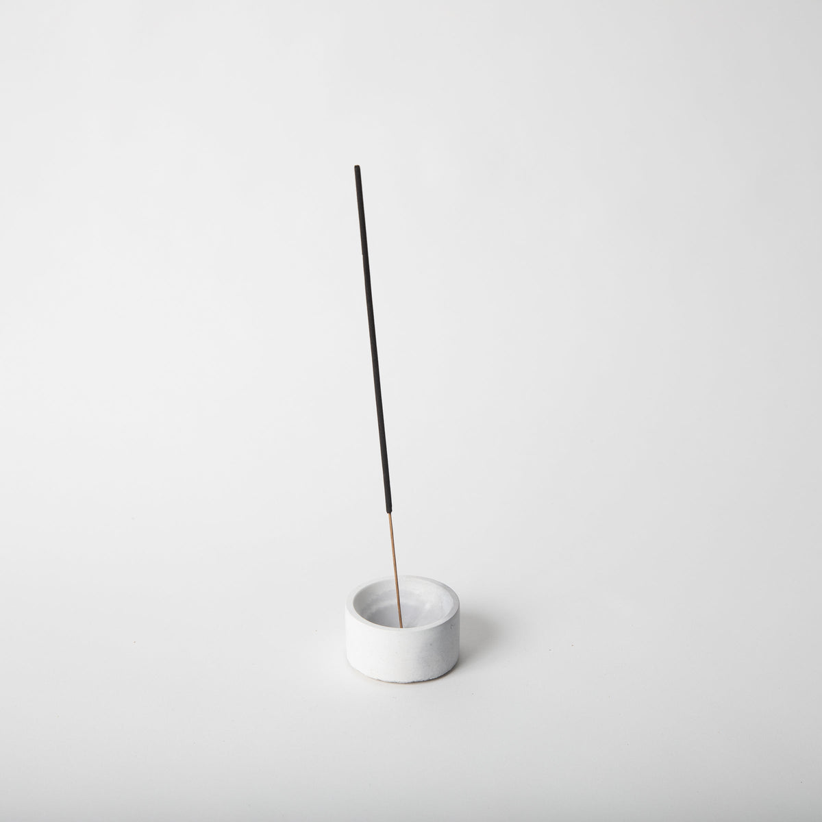 Small round incense holder with white base and upright incense stick
