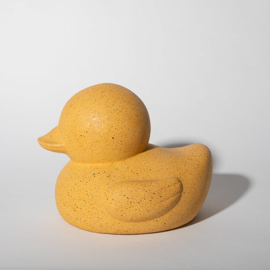 Marigold rubber duck sculpture in side profile, speckled yellow texture