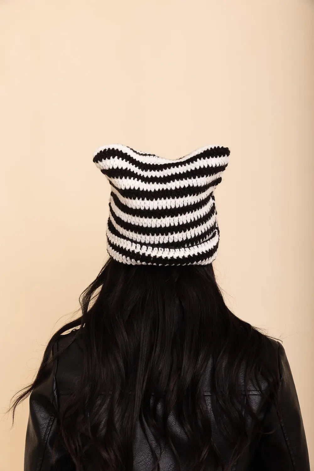 Black and white striped cat-ear crochet beanie, back view on model