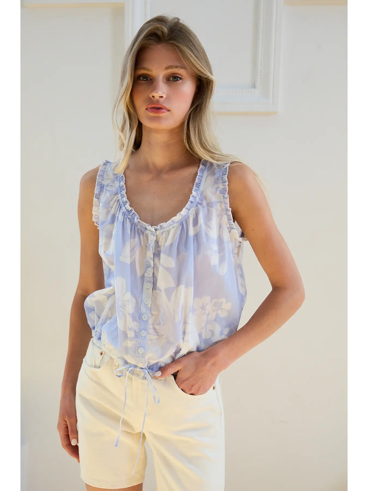 Plumeria Top in pale blue floral print with ruffled neckline, front buttons, and drawstring hem