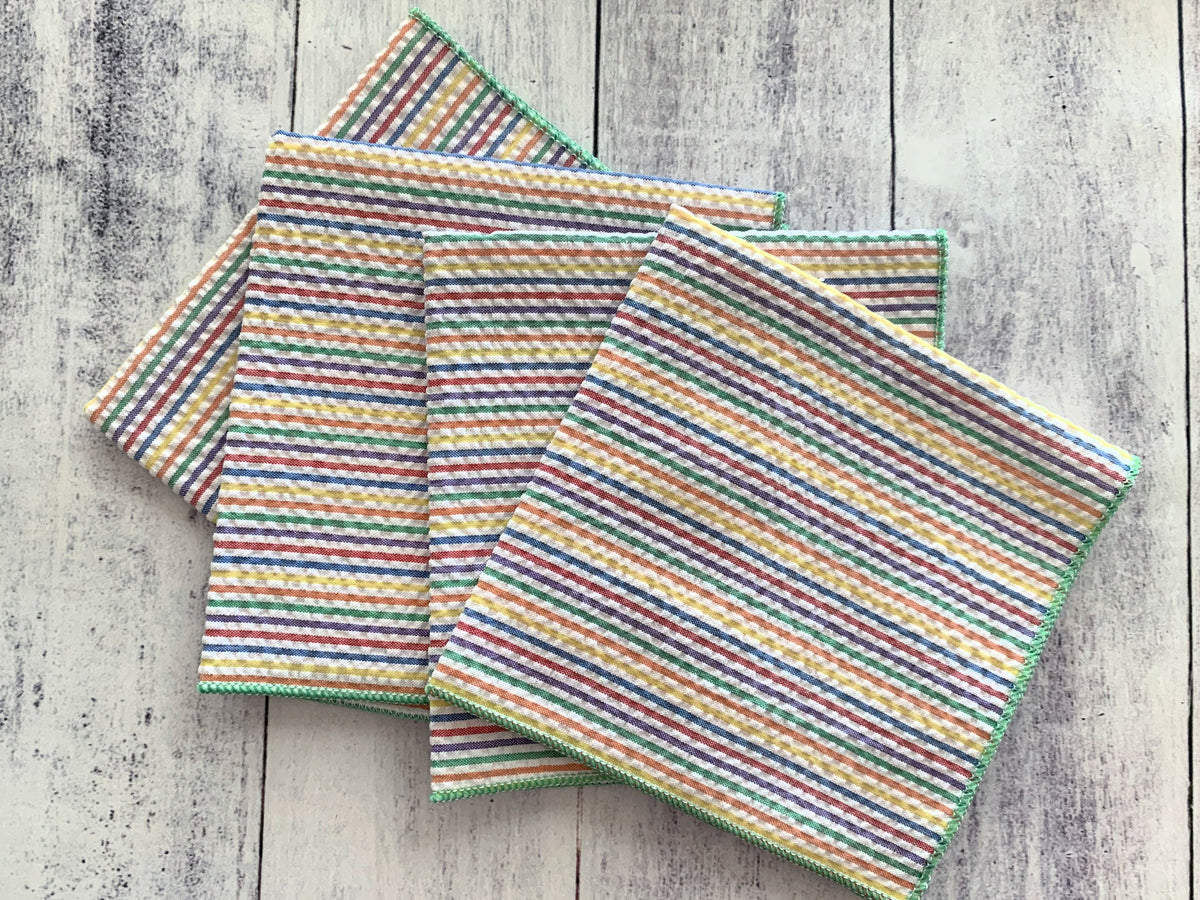 Four rainbow-striped seersucker cloth napkins, layered and spread flat
