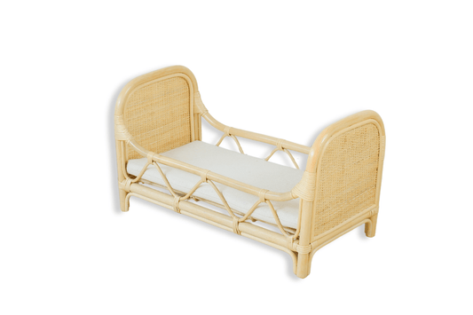 Natural rattan doll bed with woven end panels and a pale mattress