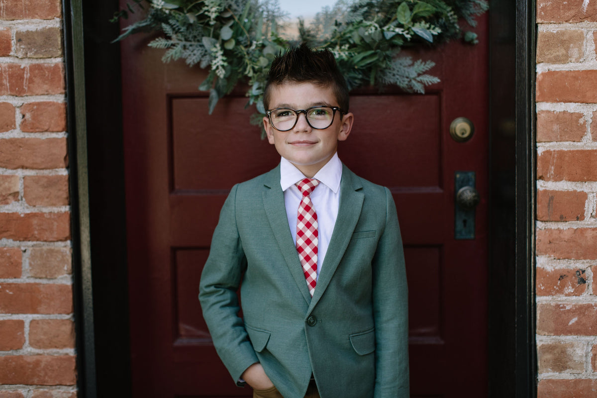 Red and white plaid necktie on a boys suit jacket, front portrait view