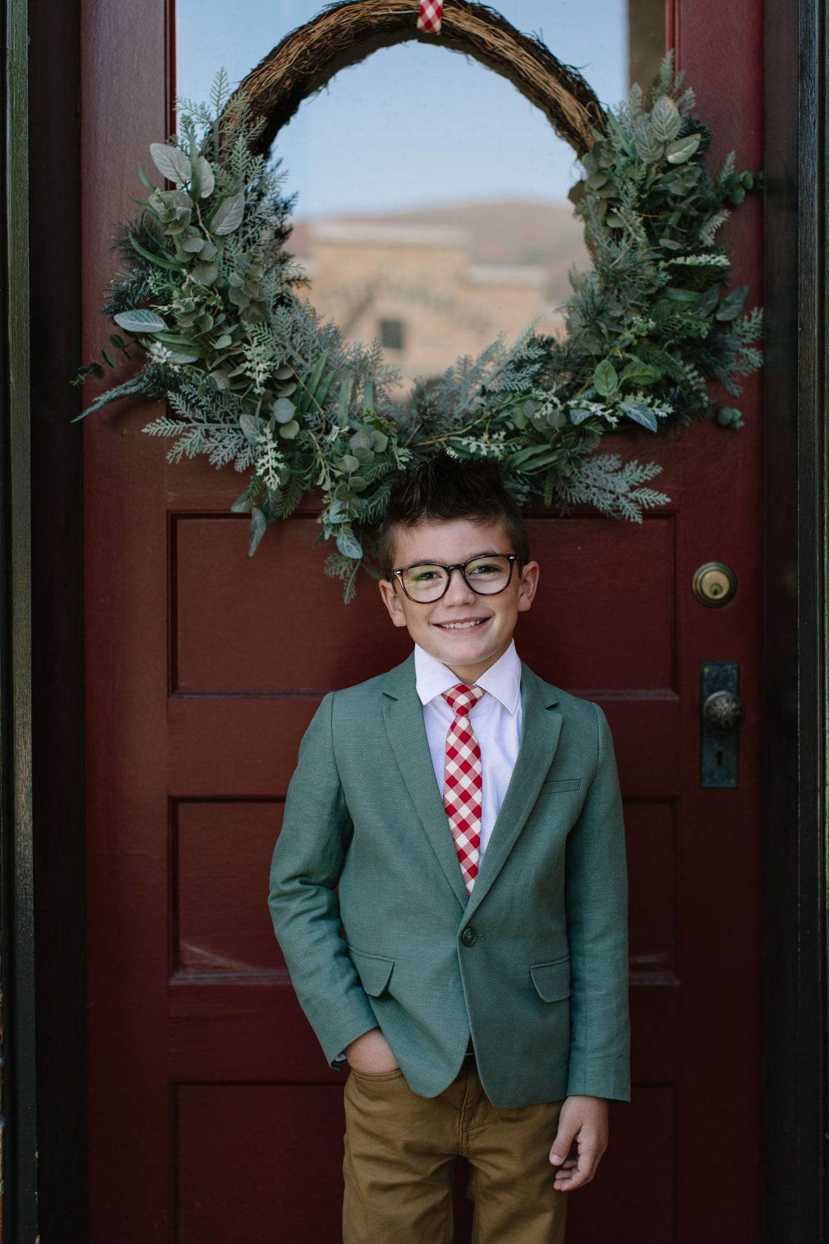 Boys red plaid neck tie on white shirt with green blazer, front view