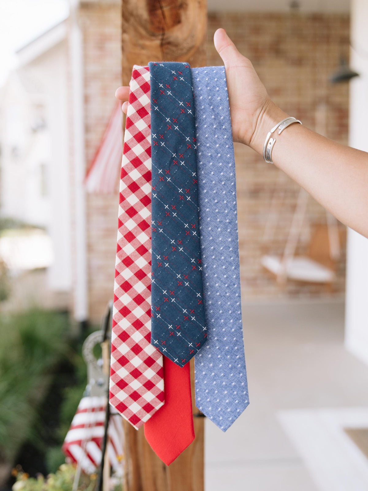 Men's red-and-cream plaid necktie held up with a blue patterned tie