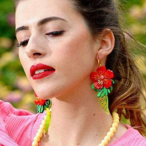 Red tropical flower earrings worn on ear: red blossoms, green leaves, light green cone drops